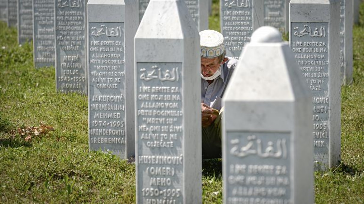رجل يصلي جالسًا بين حجارة القبور في بوتوكاري بالقرب من سريبرينيتشا – البوسنة. 2020/07/11 – حقوق النشر كما سوفتيك/أ ب